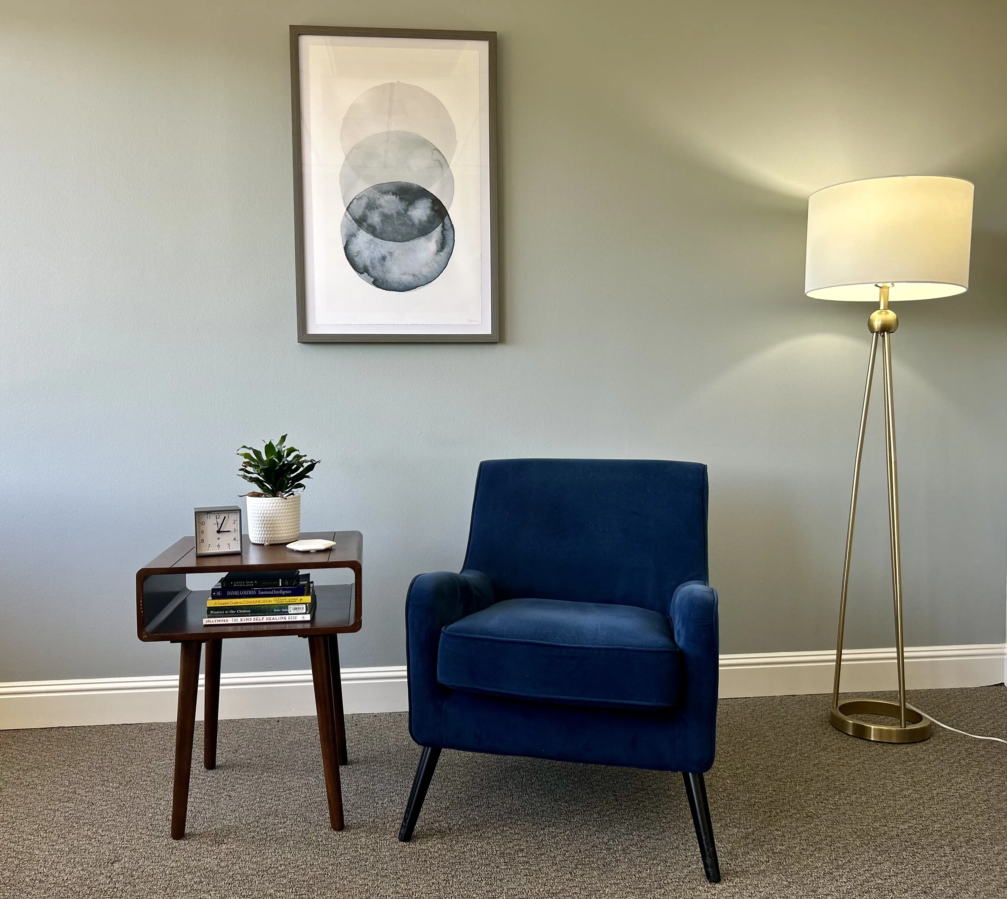 Chelsea's therapy office — a calm room with a blue velvet chair, warm lamp, and minimal art