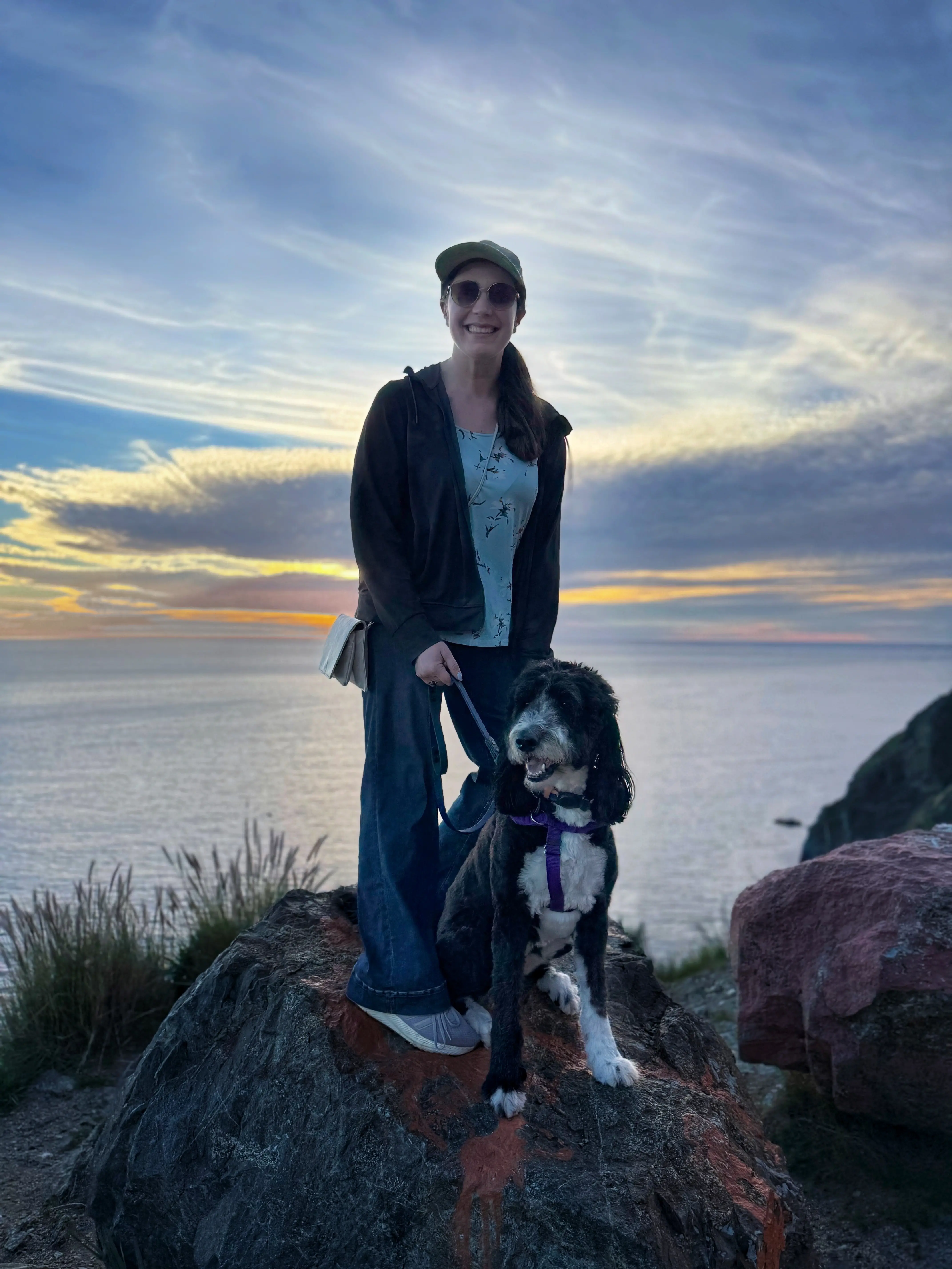 Chelsea Fenton with Kulfi, her therapy dog in training, at sunset by the ocean